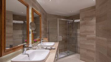 Une salle de bain moderne avec deux lavabos, une douche à l’italienne en verre et un grand miroir.