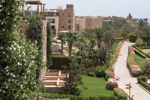 A landscaped garden with palm trees, a pathway, and a building with a traditional design.