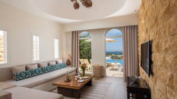 A modern living room with a sofa, coffee table, and a TV mounted on a stone wall.