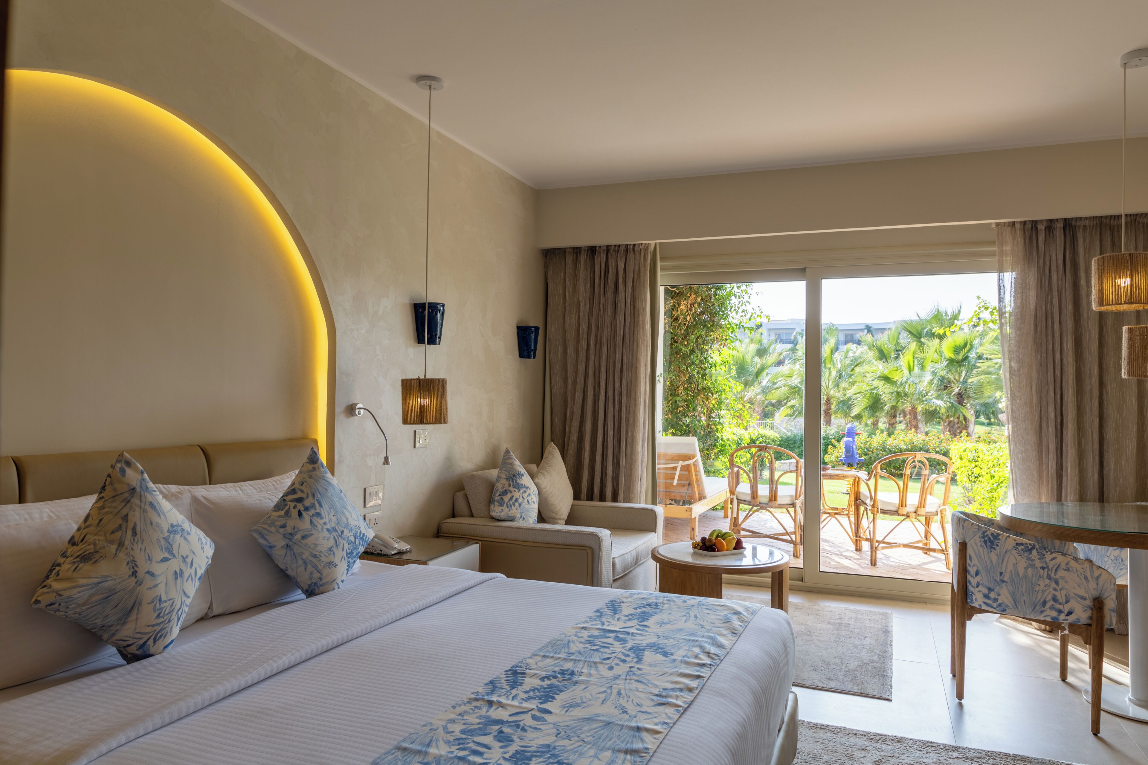 Ein Hotelzimmer mit Bett, einer Couch, einem Esstisch und Blick ins Freie.