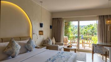 Ein Hotelzimmer mit Bett, einer Couch, einem Esstisch und Blick ins Freie.