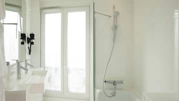 A modern bathroom with a large window, a bathtub, and a shower area.