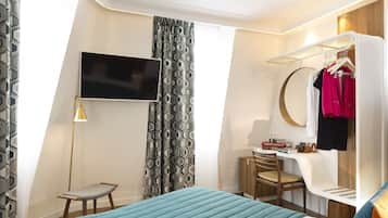 Una habitación de hotel moderna con cama, escritorio, silla, televisor, armario y perchero.