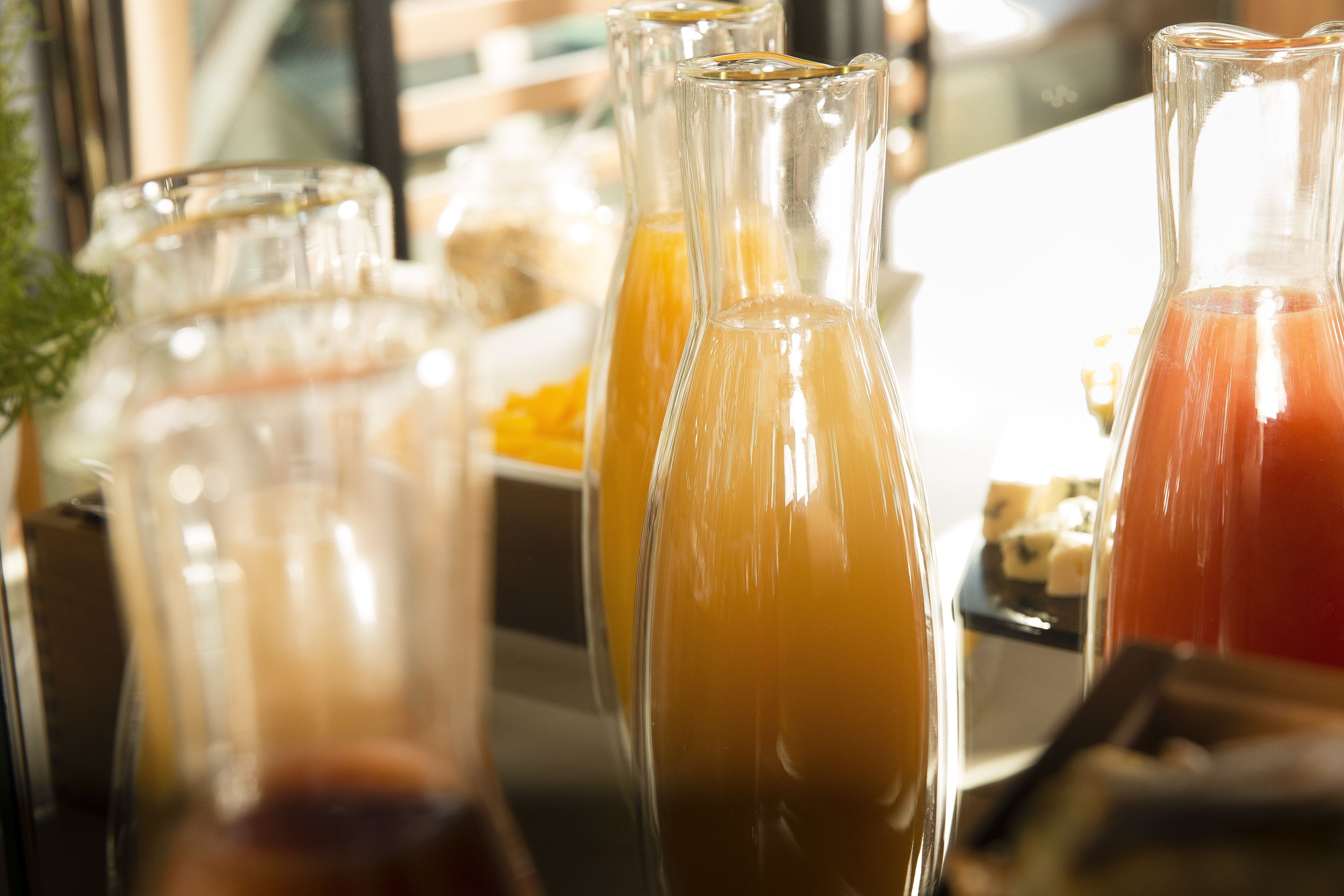 A close-up of three glass bottles with different colored liquids, likely juices or smoothies, on a tray.