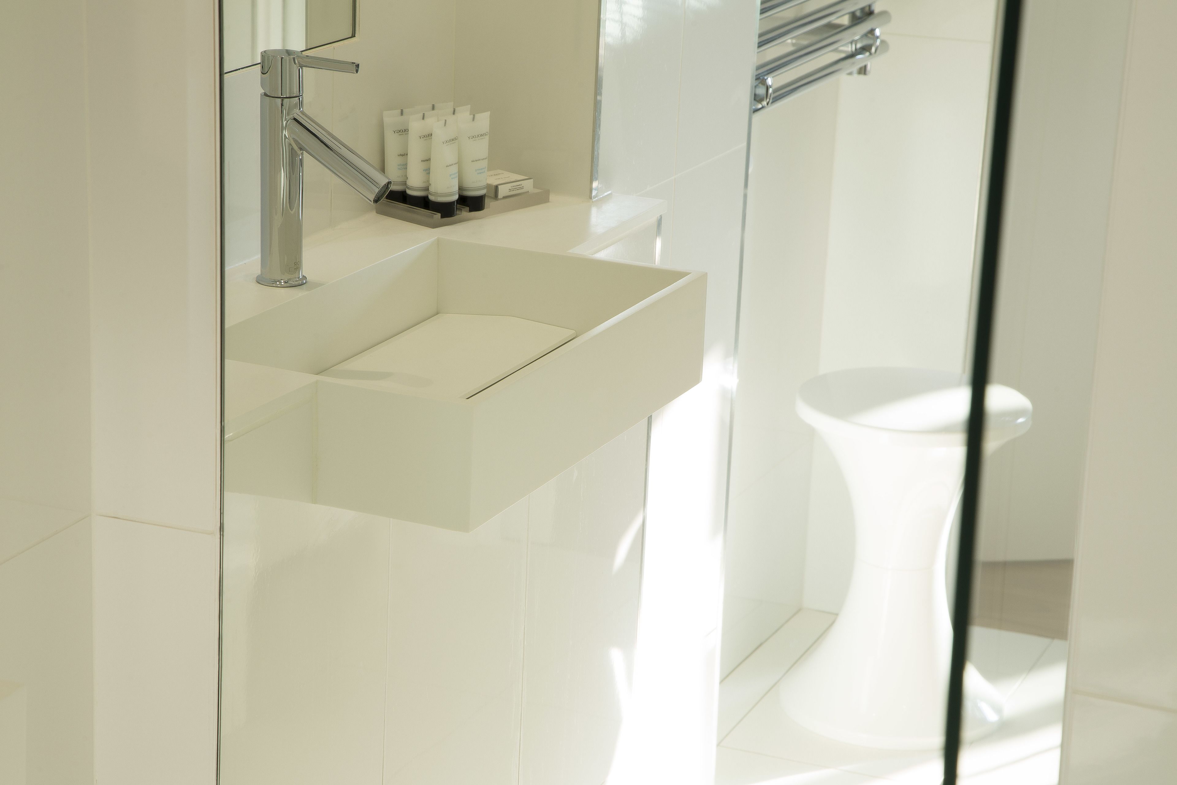 A modern bathroom with a white sink, mirror, and toilet.