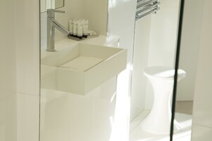 Un bagno moderno con lavandino, specchio e servizi igienici bianchi.