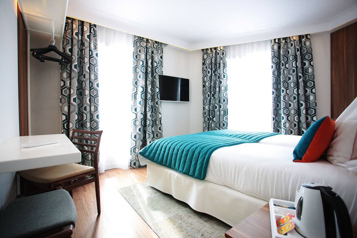 A hotel room with a bed, a desk, a chair, a TV, and a coffee maker.