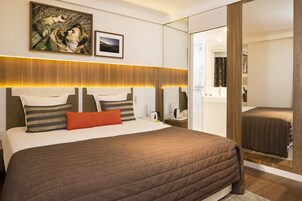 Una moderna camera d'albergo con un letto grande, un comodino, uno specchio e opere d'arte alle pareti.