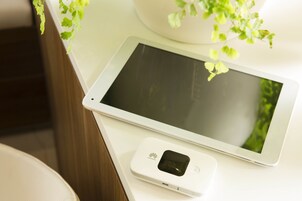 Un tablet e un piccolo dispositivo su una superficie bianca.
