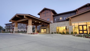 A multi-story hotel with a covered entrance, stone facade, and large windows. - King's Pointe Waterpark Resort (Storm Lake)