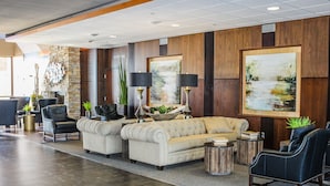 A lobby with a seating area, a reception desk, and a large painting on the wall. - King's Pointe Waterpark Resort (Storm Lake)