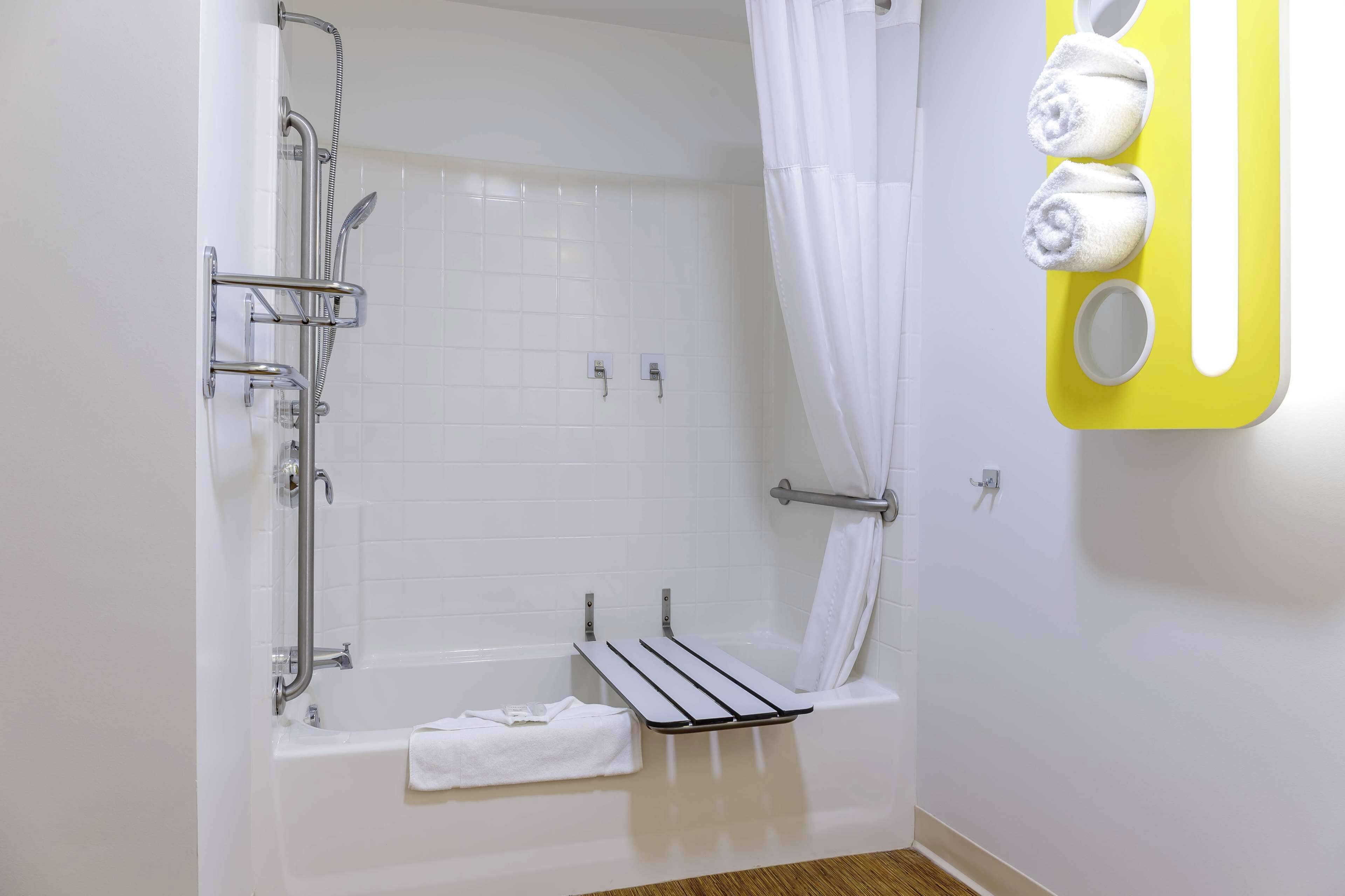 A bathroom with a bathtub, shower, and a towel rack with towels.