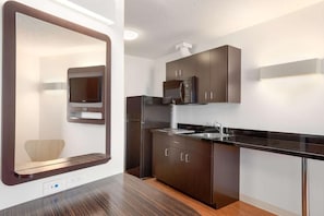 Una cocina moderna con armarios oscuros, encimera de acero inoxidable y microondas integrado.