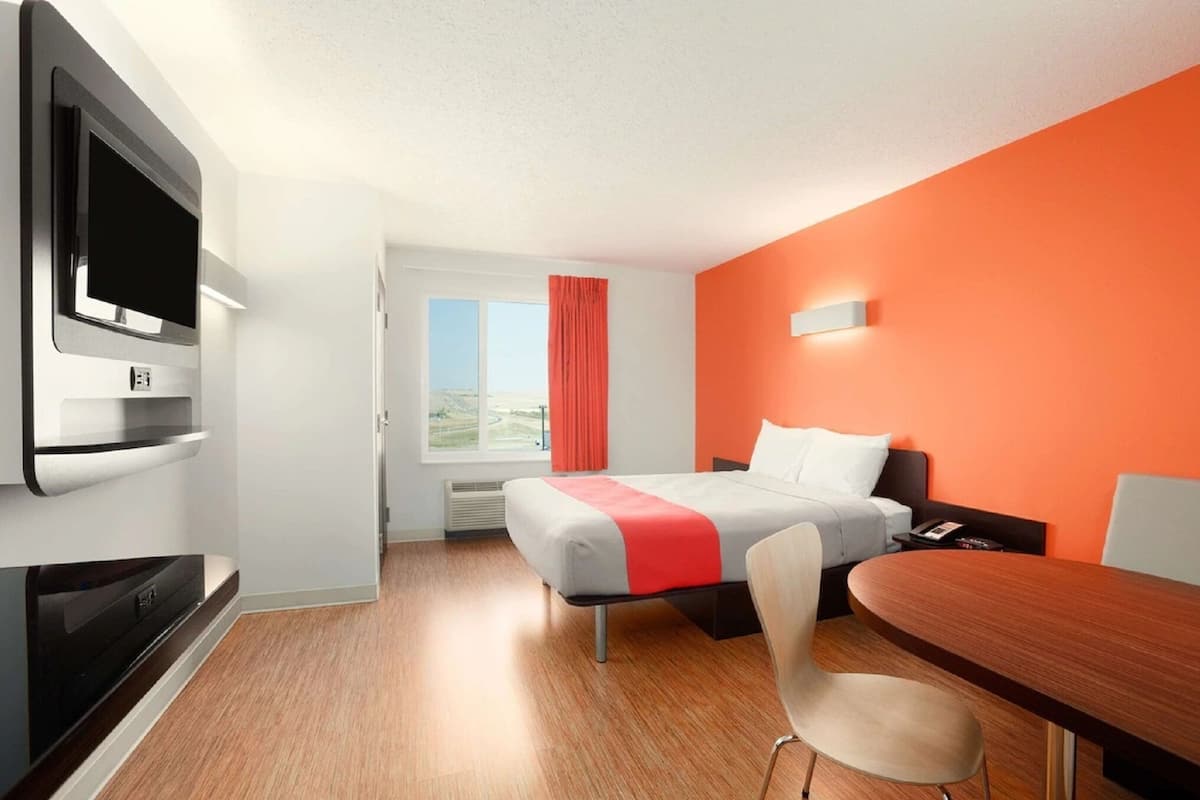 Une chambre d’hôtel avec un lit, une télévision, un bureau et une fenêtre donnant sur un paysage agréable.