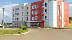 A multi-story hotel with a prominent red and white facade, featuring a large '6' sign on the top right corner. - Motel 6 Swift Current, SK (Swift Current)