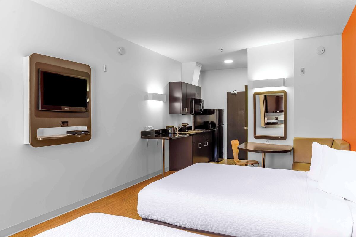 Une chambre d’hôtel équipée d’un lit, d’un bureau, d’un four à micro-ondes et d’une télévision.