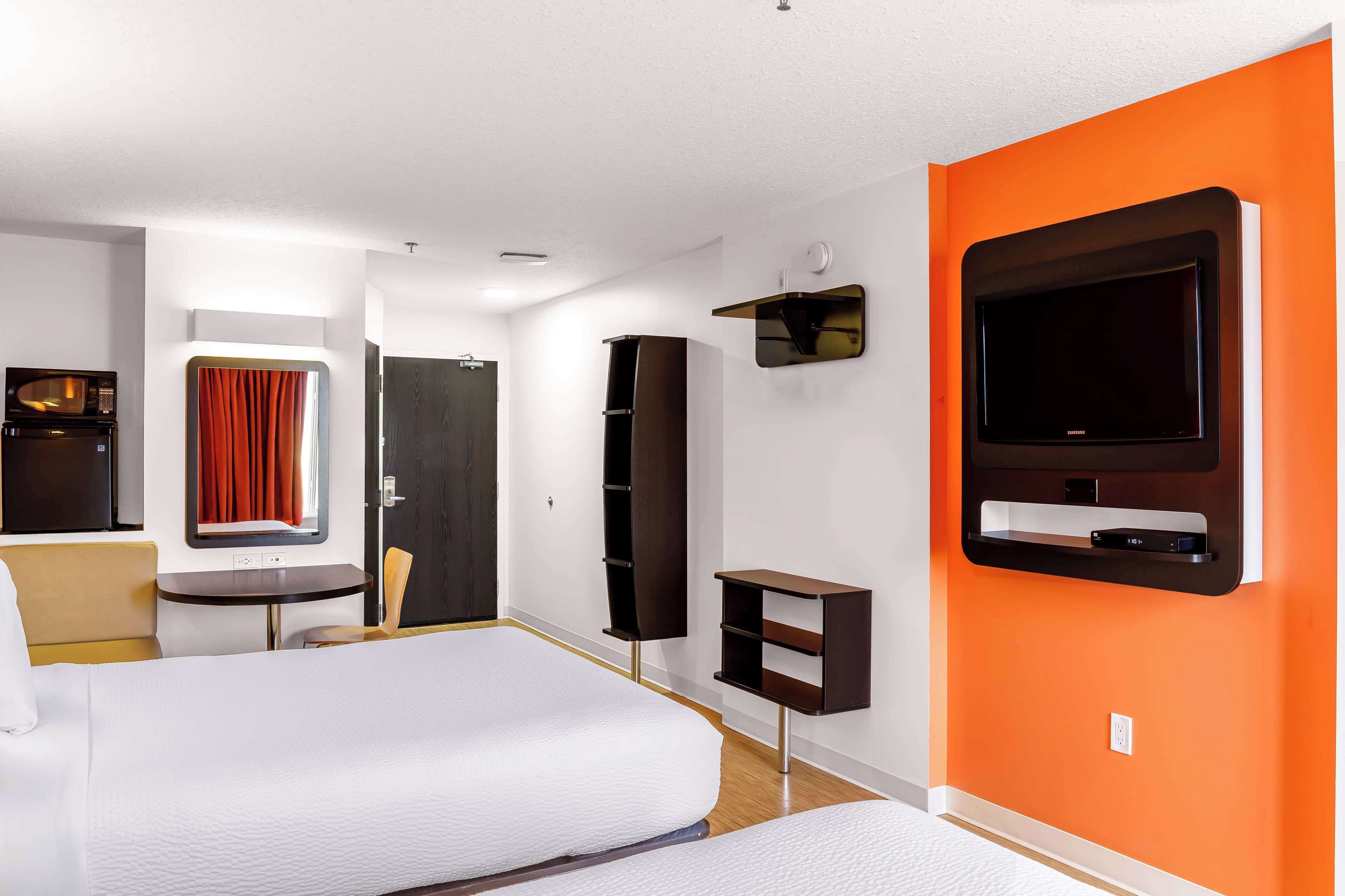 Una habitación de hotel con cama, televisión, escritorio y armario.