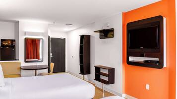 Una habitación de hotel con cama, televisión, escritorio y armario.