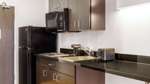A compact kitchen with a refrigerator, microwave, toaster, and sink. - Motel 6 Swift Current, SK (Swift Current)