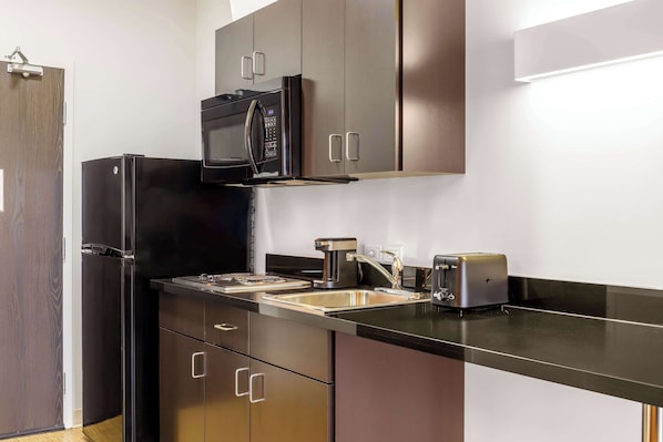 A compact kitchen with a refrigerator, microwave, toaster, and sink. - Motel 6 Swift Current, SK (Swift Current)