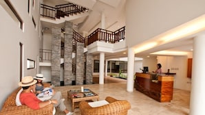 Eine geräumige Lobby mit Empfangstresen, Korbsesseln und einer Treppe.