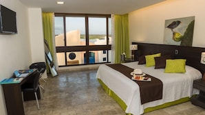 Ein Hotelzimmer mit Bett, Schreibtisch und einem großen Fenster mit Vorhängen.
