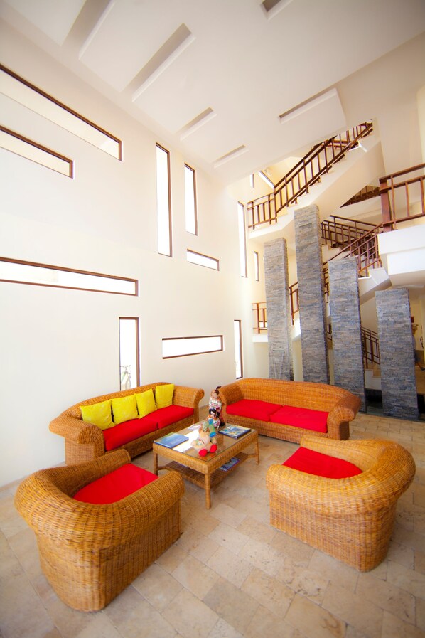 A spacious living area with wicker furniture, a coffee table, and a staircase leading to an upper level. - Isla Sol by Hotel Solymar (Puerto Ayora)