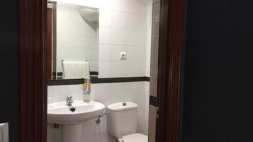A bathroom with a white sink, a toilet, and a mirror.