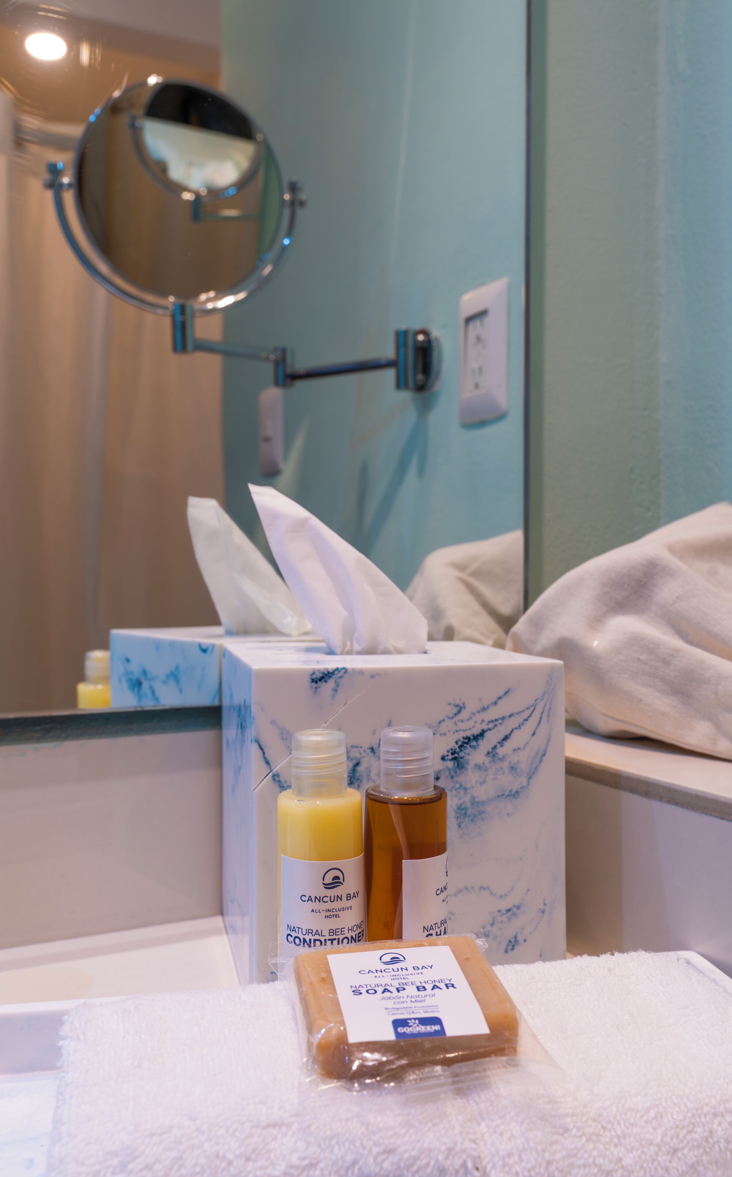 A bathroom with a mirror, a tissue box, and two bottles of lotion.