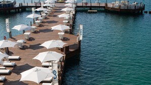 A pier with rows of sun loungers and umbrellas, a wooden deck, and a boat docked at the end. - B Pichilingue Acapulco (Acapulco)