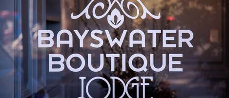 A window with the text "BAYSWATER BOUTIQUE LODGE" in white letters.