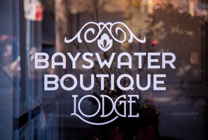 Une fenêtre sur laquelle on peut lire, en lettres blanches, le texte « BAYSWATER BOUTIQUE LODGE ».