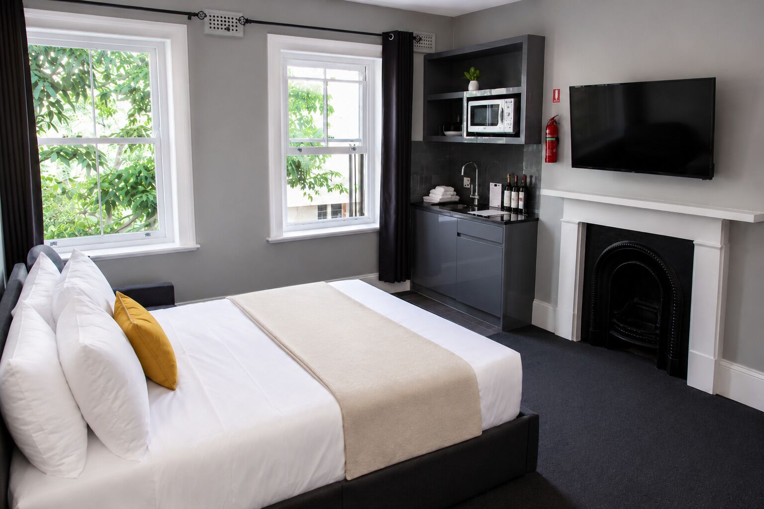 Une chambre d’hôtel équipée d’un lit, d’une télévision, d’un four à micro-ondes, d’une cheminée et offrant une vue sur la verdure.