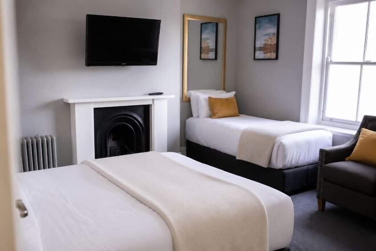 Une chambre d’hôtel avec une cheminée, un lit, un canapé, une télévision et une fenêtre.