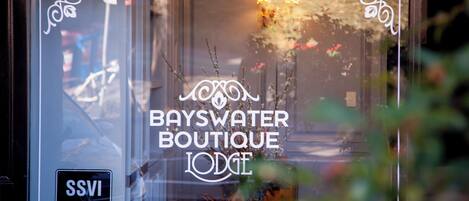A storefront with the text "BAYSWATER BOUTIQUE LODGE" and a phone number.