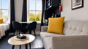 Una habitación de hotel moderna con cama, sofá, mesa de comedor y zona de cocina.