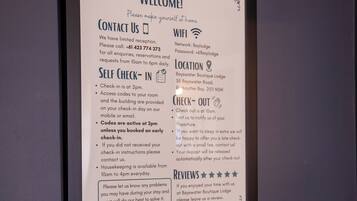 A framed welcome sign with hotel contact info, WiFi details, check-in/check-out times, and room locations.
