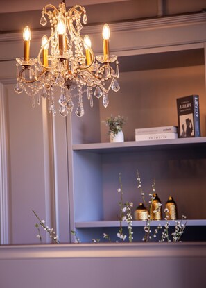 Un candelabro con varias luces, una estantería llena de libros y objetos decorativos, y un jarrón con flores.