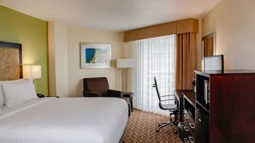 A hotel room with a large bed, a desk, a chair, a TV, and a painting on the wall.