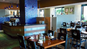 Un restaurante con mostrador, mesas, sillas y vistas al exterior.