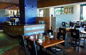 Ein Restaurant mit Theke, Tischen, Stühlen und Blick ins Freie.
