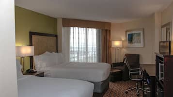 Une chambre d’hôtel avec deux lits, un bureau, une chaise, une lampe et un tableau au mur.