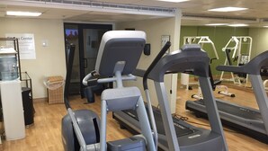 Un gimnasio con cintas de correr, elípticas y un dispensador de agua.