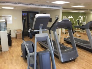 Ein Fitnessraum mit Laufbändern, Crosstrainern und einem Wasserspender.