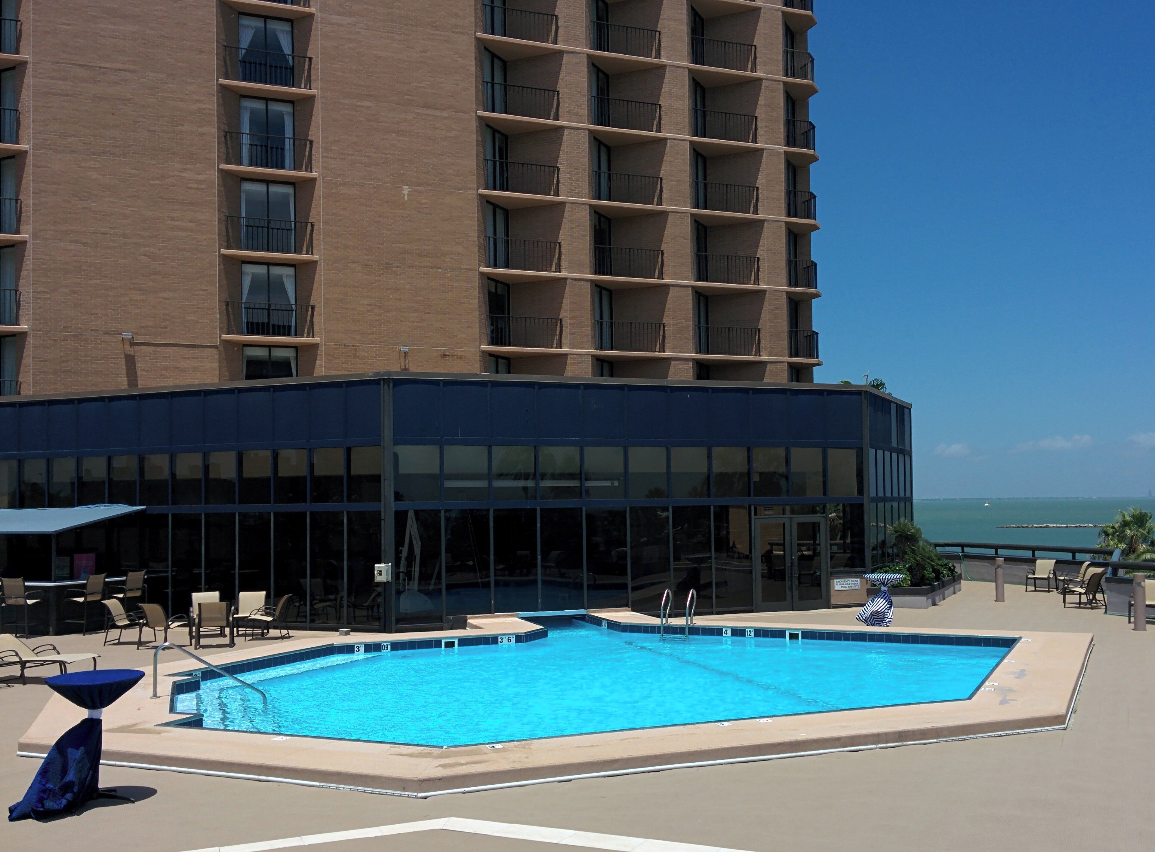 A hotel with a swimming pool, outdoor seating, and a view of the ocean.