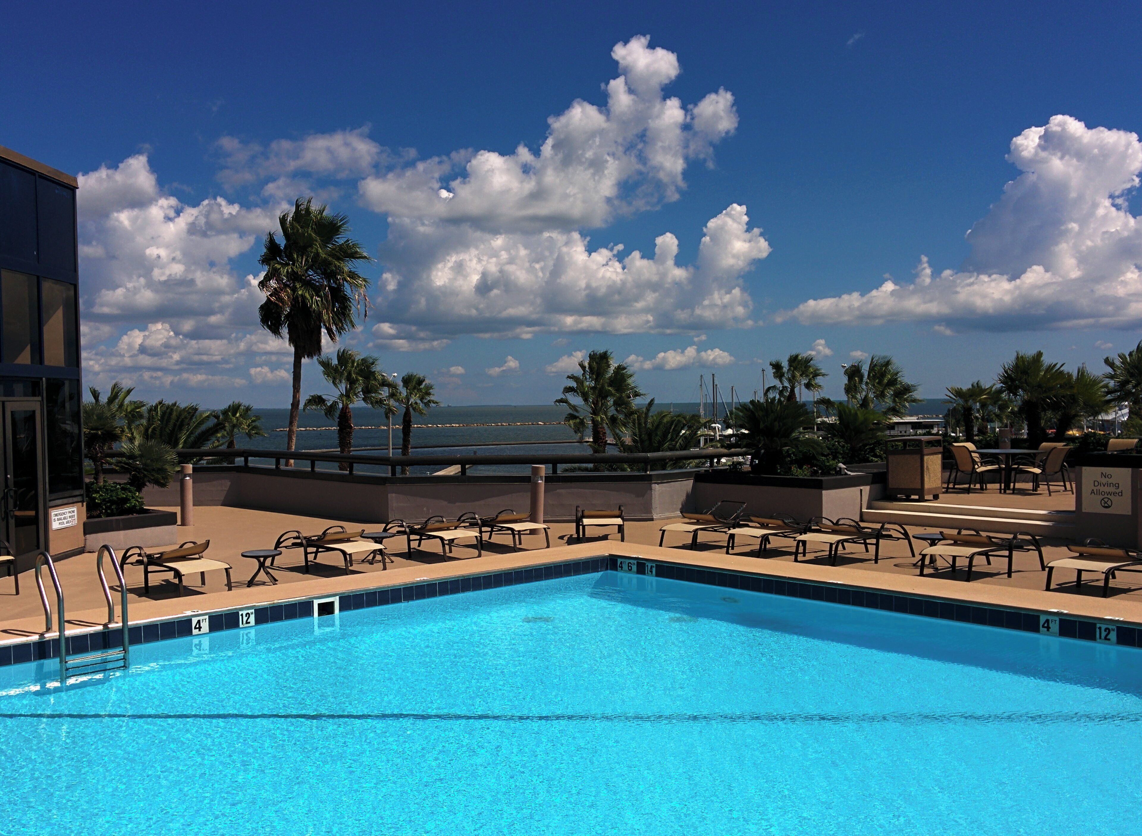 Una piscina con sillones de descanso y vista al océano.