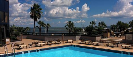 A swimming pool with lounge chairs and a view of the ocean.