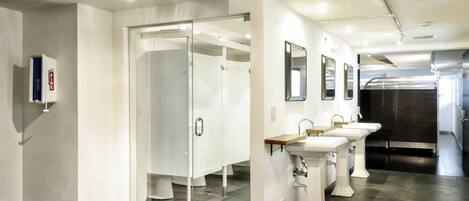 A modern restroom with glass doors, multiple sinks, and a fire extinguisher on the wall.