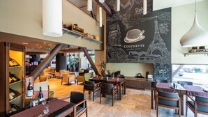 A restaurant with a high ceiling, exposed beams, and a chalkboard wall with a map and text. Tables are set with wine glasses and menus. - Kronwell Brasov Hotel (Brasov)