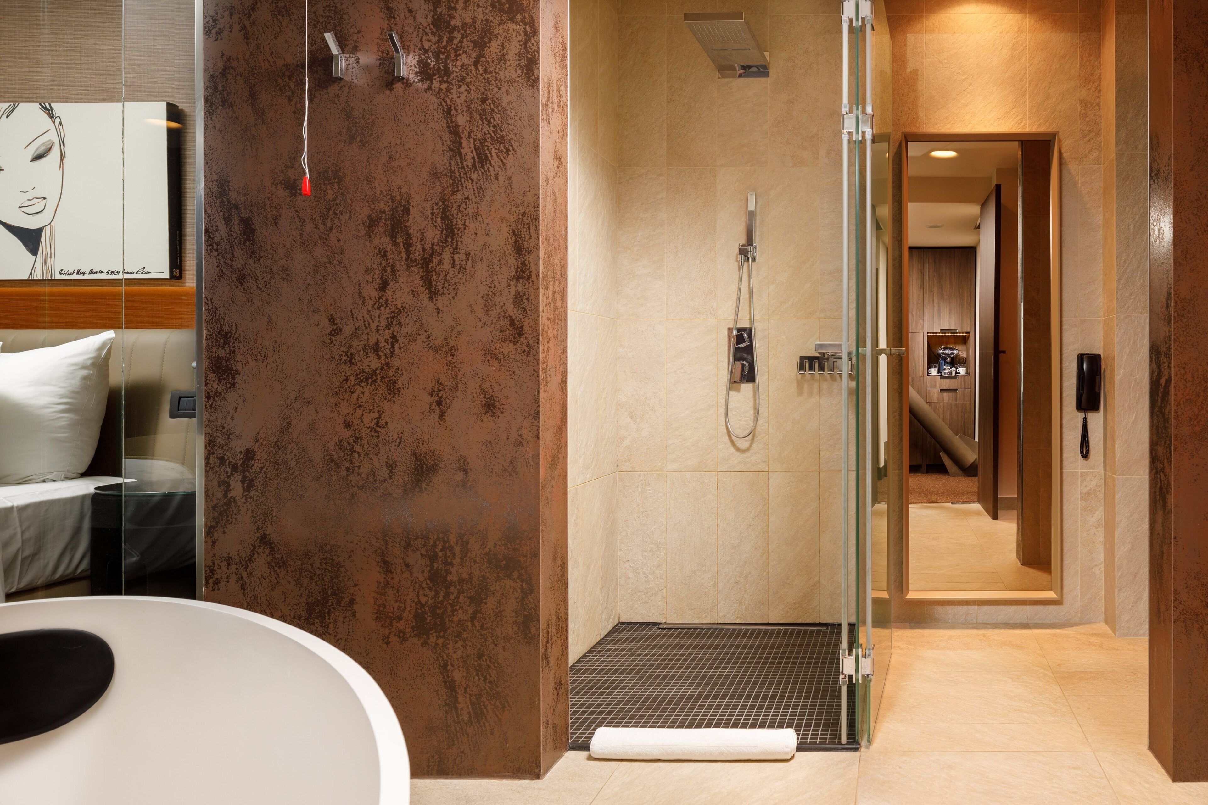 A modern bathroom with a glass shower enclosure, a visible toilet, and a towel on the floor.